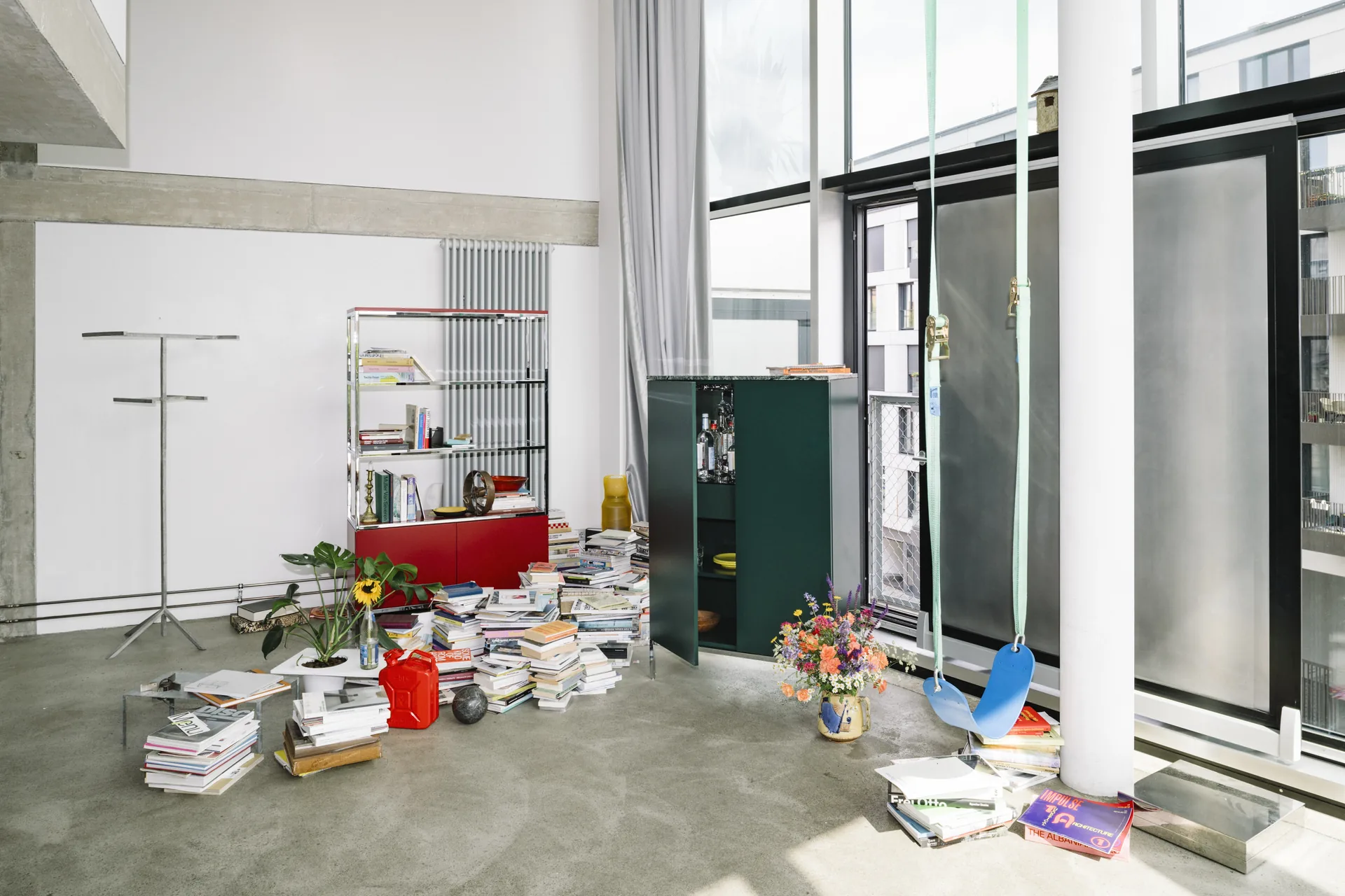 Estantería alta abierta Knoll Chermayeff Storage y armario verde en un loft de doble altura con libros